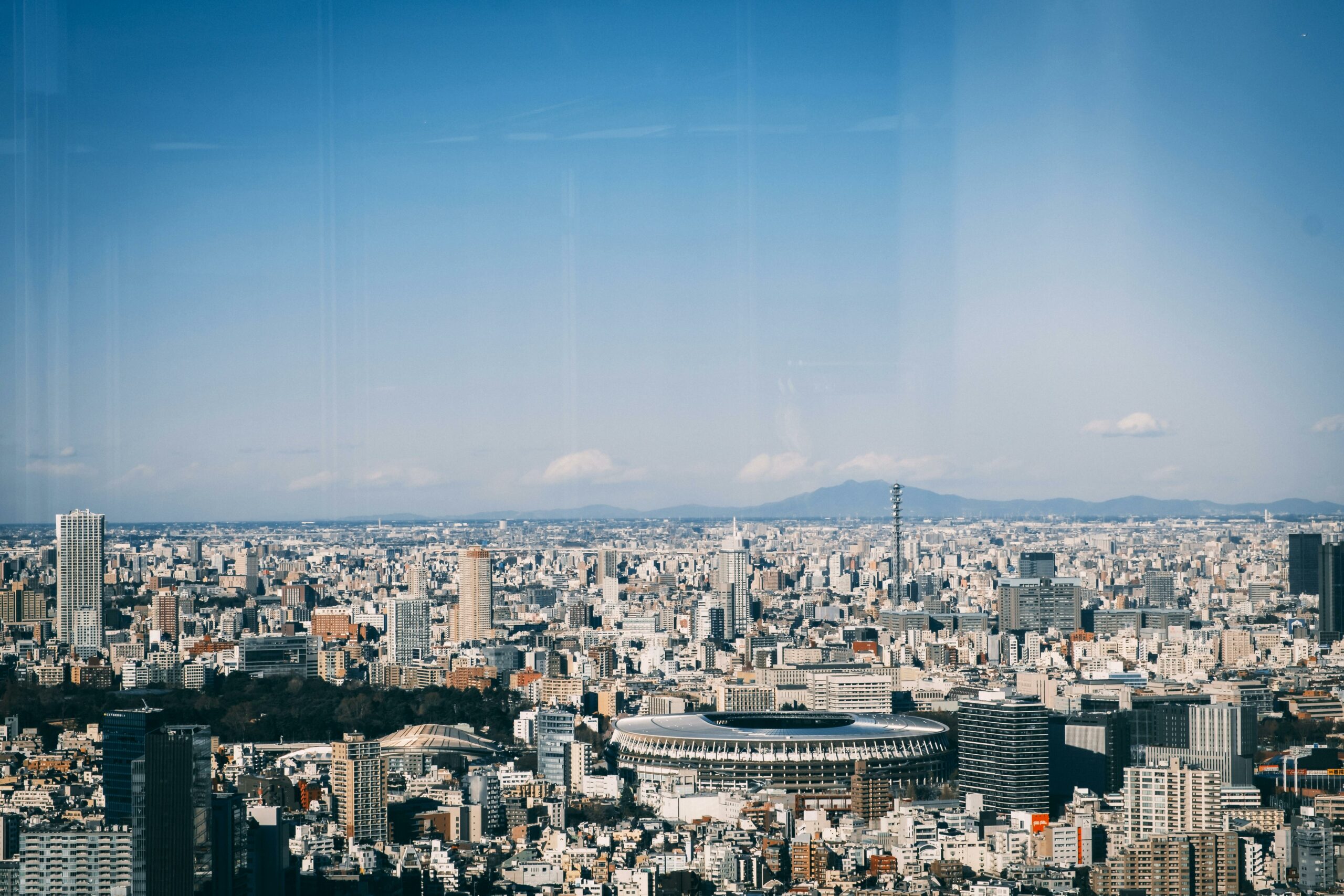 An awe-inspiring view of Tokyo cityscape featuring the New National Stadium under a clear blue sky.